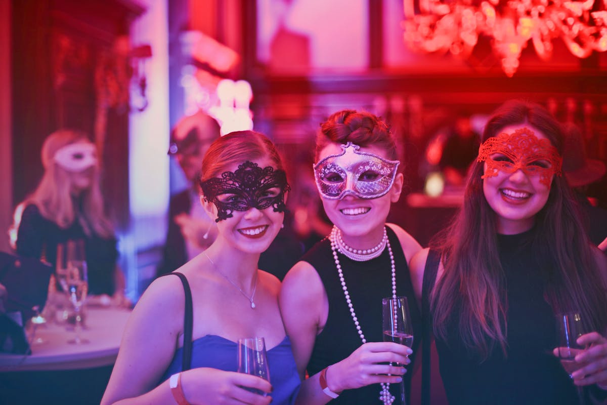 Three women in masquerade masks at a party