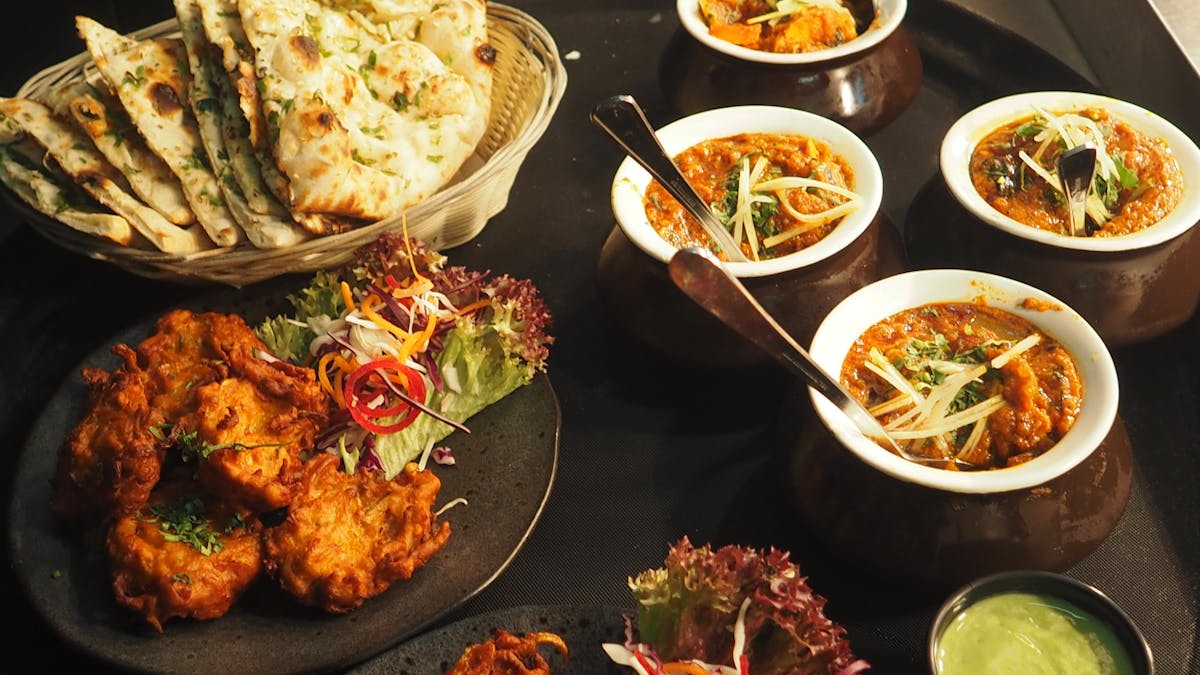 Bowls of curry, naan, and fried chicken on a table