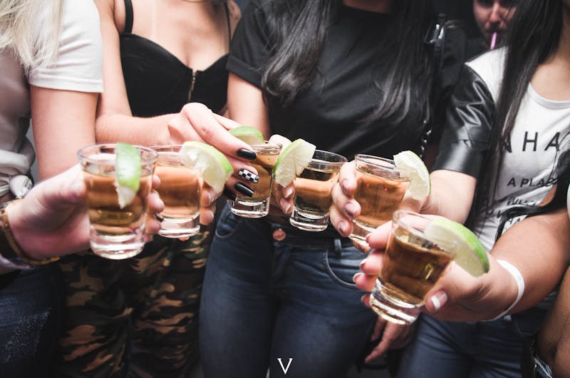 Friends holding a round of shots toward the camera